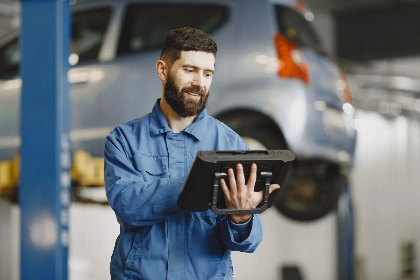 A technician holding a tablet, with a workshop lift in the background